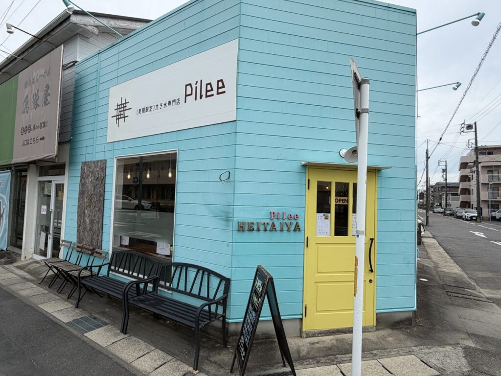 Pilee(ピリー)の外観 水色の建物に黄色いドア